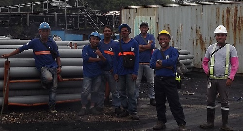 Workers take a group photo in front of the materials


